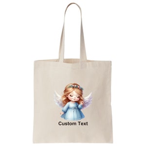 Puede incluir: Una bolsa de tela beige con una ilustraci&oacute;n blanca de un &aacute;ngel con cabello rubio, ojos azules y un vestido azul claro. El &aacute;ngel lleva una corona de flores. El texto "Custom Text" est&aacute; impreso en la bolsa.