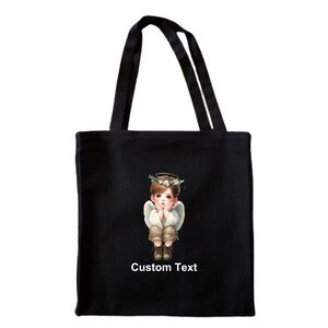 May include: Black tote bag with a white angel illustration and the text "Custom Text".