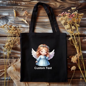 Puede incluir: Bolsa de tela negra con una ilustraci&oacute;n de un &aacute;ngel blanco y el texto "Custom Text".