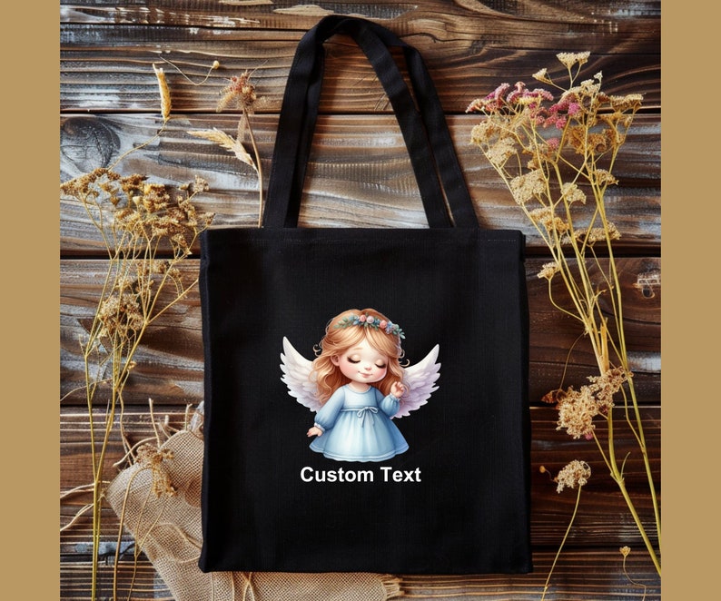 Puede incluir: Bolsa de tela negra con una ilustraci&oacute;n de un &aacute;ngel blanco y el texto "Custom Text".