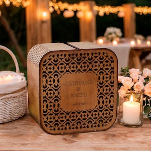 May include: A wooden card box with an intricate cutout design, personalized with the names "Catherine & Joseph" and a date. A white wicker basket and lit candles are on a wooden table, with string lights in the background.