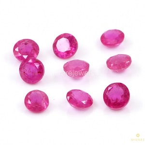 May include: A collection of eight round and oval-cut, vibrant pink gemstones. The gems are scattered on a white surface, showcasing their polished facets and rich color. The gemstones vary slightly in size and shape, reflecting natural variations.