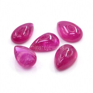 Op de afbeelding: Vijf traanvormige, gepolijste magentakleurige edelstenen gerangschikt in een groep. Elke steen heeft een glad oppervlak in cabochon-stijl met zichtbare lichtreflecties. De tekst "mirarejewels" staat in het midden en "MIRARE" onderaan.