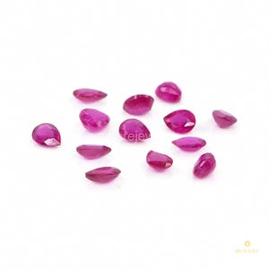 May include: A collection of thirteen loose, pear-shaped faceted rubies with a vibrant deep pinkish-red hue. Each gemstone features a pointed end and a rounded base, displaying multiple polished facets that reflect light across their surfaces.