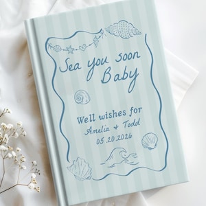 May include: A light blue book with vertical stripes and the text "Sea you soon Baby". The cover features seashell and wave illustrations. The book includes the text "Well wishes for Amelia + Todd 05.20.2026".