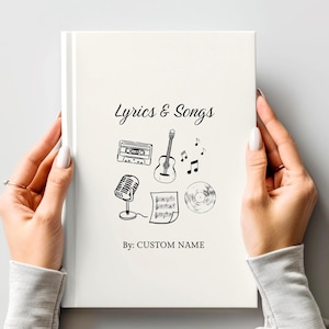 May include: A white notebook titled "Lyrics & Songs" with black illustrations of a cassette tape, guitar, microphone, musical notes, and a record. The text "By: CUSTOM NAME" is below the illustrations.