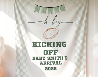 Op de afbeelding: Een rechthoekige stoffen banner met een lichtgroene en witte geblokte rand. Het midden bevat een groene vlaggenlijn, de tekst "oh boy", een illustratie van een football en de tekst "KICKING OFF BABY SMITH'S ARRIVAL 2026" in het groen.