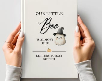 May include: A white hardcover book with the text OUR LITTLE Boo IS ALMOST DUE and LETTERS TO BABY SUTTER printed in black. The cover features a small illustration of a ghost wearing a black witch hat and a tiny orange pumpkin icon.
