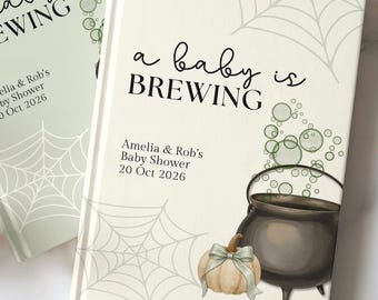 May include: Two hardcover books with light green and cream covers featuring spider web illustrations, green bubbles, a black cauldron, and a pumpkin with a bow. The text reads a baby is BREWING, Amelia & Rob's Baby Shower, and 20 Oct 2026.