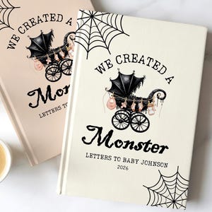 Peut inclure: Deux journaux à couverture rigide sur le thème d'Halloween. Les couvertures sont crème et rose clair, avec un motif de toile d'araignée noire. Le texte se lit "WE CREATED A Monster" avec une illustration de landau. Le texte du bas se lit "LETTERS TO BABY JOHNSON 2026".