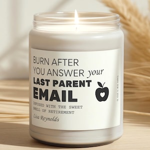 Peut inclure: Une bougie blanche allumée dans un pot en verre transparent. L'étiquette indique "BURN AFTER YOU ANSWER your LAST PARENT EMAIL" avec un dessin de pomme. La bougie est parfumée au parfum de la retraite. La bougie est de 255 grammes et brûle pendant 40 heures.