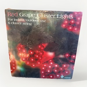 May include: A package of red grape cluster lights for indoor/outdoor use. The box features a graphic of red grape lights and the text "Red Grape Cluster Lights" and "6 cluster string".