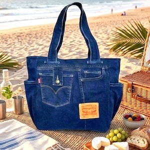 Può includere: Una borsa tote in denim blu scuro con due manici, tasche laterali e una tasca centrale con chiusura a bottone. Una toppa color cuoio con la scritta Levi Strauss & Co. è cucita sul davanti, insieme a una piccola etichetta rossa del marchio.