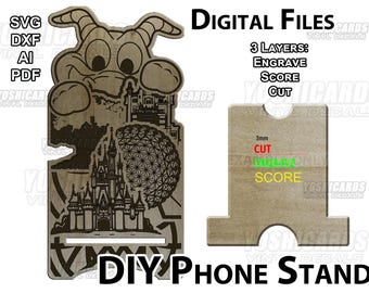 Puede incluir: Soporte de teléfono DIY de madera con un diseño de personaje de dibujos animados, un castillo y una esfera geodésica. El soporte incluye el texto "Digital Files" y "DIY Phone Stand". El soporte es de madera y tiene una ranura para un teléfono.