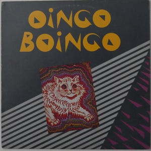 Op de afbeelding: Albumhoes voor Dingo Boingo. De naam van de band staat in gele, gestileerde tekst. Een kleurrijke illustratie van een kat staat in het midden onderaan. De achtergrond is donkergrijs met diagonale strepen en paarse driehoeken.