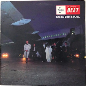 May include: Album cover for The English Beat's "Special Beat Service." The image shows a group of people in suits and robes standing near an airplane at night. The album title and band name are in a red box with a plane graphic.