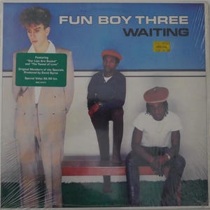 May include: Album cover for Fun Boy Three's "Waiting." The album art features three men in front of a blue background. The album title and band name are in white text. A green sticker lists song titles and the producer. The album is sealed in plastic.