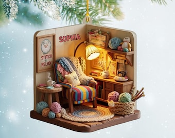 May include: A decorative ornament featuring a miniature cozy room with a chair, lamp, and yarn. The ornament has a small framed cross-stitch that says "Stitch & Relax" and the name "Sophia". A perfect gift for a crafter.
