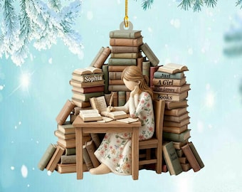 May include: A decorative ornament featuring a girl writing at a desk surrounded by stacks of books. The ornament has a gold string for hanging. The text "Sophia" is on one stack of books, and "Just A Girl Who Loves Books" is on another.