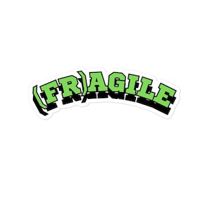 以下が含まれることがあります： 太字の緑色の3Dフォントで「FRAGILE」という単語が書かれたステッカー。単語はアーチ状で黒で縁取られ、白い背景に配置されています。このデザインは人目を引き、読みやすくなっています。