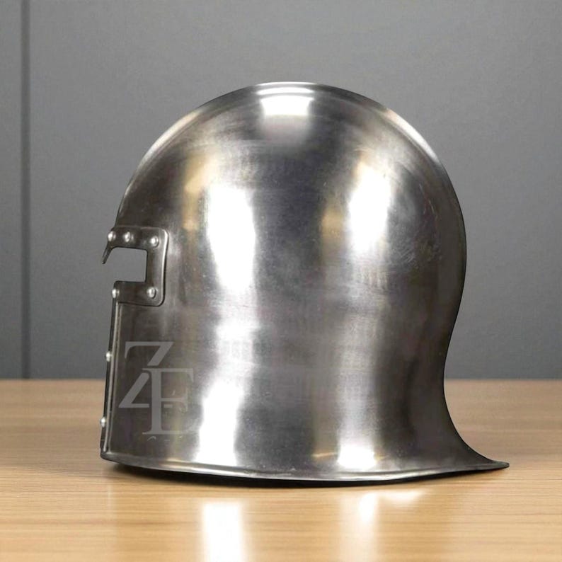 K&ouml;nnte beinhalten: Ein polierter, silberfarbener Metallhelm mit abgerundeter Oberseite und einem ausgestellten Nackenschutz. Der Helm hat einen rechteckigen Ausschnitt an der Seite und ein stilisiertes Logo. Die Oberfl&auml;che reflektiert das Licht und hebt seine glatte Textur hervor. Der Helm ist wahrscheinlich f&uuml;r historische Nachstellungen oder Ausstellungen.