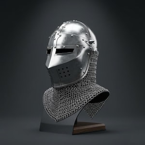 May include: A polished steel knight helmet featuring a pointed visor with horizontal eye slits and a series of small ventilation holes. The helmet is attached to a silver-colored chainmail aventail that drapes over the shoulders and neck area.