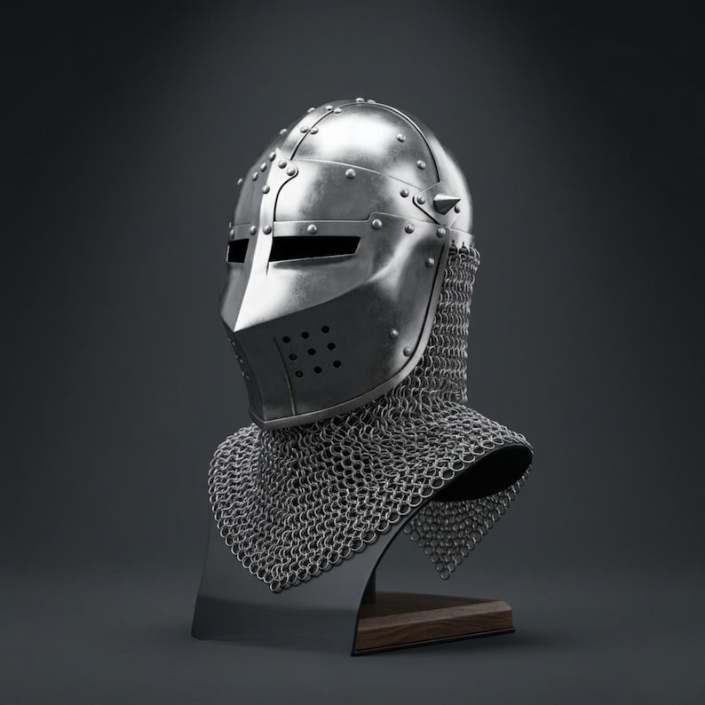 May include: A polished steel knight helmet featuring a pointed visor with horizontal eye slits and a series of small ventilation holes. The helmet is attached to a silver-colored chainmail aventail that drapes over the shoulders and neck area.