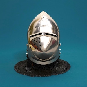 May include: A shiny silver knight's helmet with a pointed crown and a visor featuring two horizontal slits. The helmet has small holes and a smiling mouth-shaped opening. It sits on a chainmail coif.