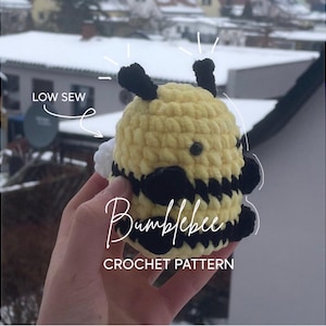 Könnte beinhalten: Gehäkelte Hummel mit gelben und schwarzen Streifen, schwarzen Fühlern und weißen Flügeln. Der Text "Bumblebee Crochet Pattern" ist sichtbar. Die Worte "Low Sew" sind ebenfalls sichtbar.