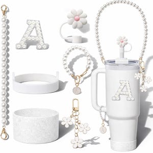 Pode incluir: Uma coleção de acessórios brancos, incluindo um copo com a letra "A", uma alça de pérolas, uma pulseira, um chaveiro e um topo de canudo em forma de flor. O copo e a letra "A" são adornados com enfeites brilhantes.