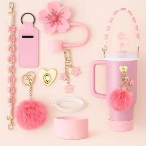 Peut inclure: Ensemble d'accessoires roses, comprenant une gourde, des porte-clés et une sangle, tous ornés de motifs floraux et en forme de cœur. La gourde a une poignée et un pompon rose duveteux. Les accessoires sont conçus pour se compléter.