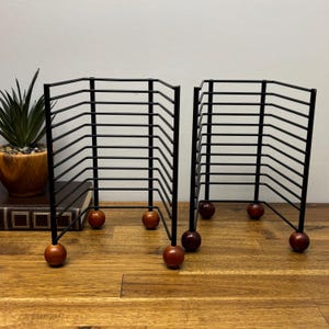 Black metal CD rack with wooden legs, retro 90s music storage, compact decorative desk stand