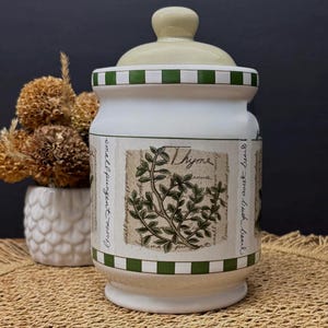 Può includere: Una tazza di ceramica bianca con manico nero e la scritta "But First, Coffee" in nero, con un carattere a mano. La tazza è su una superficie bianca.