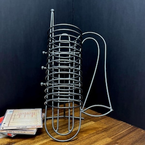 May include: A white ceramic mug with a black handle and the text "But First, Coffee" in a black, handwritten-style font. The mug is on a white surface.