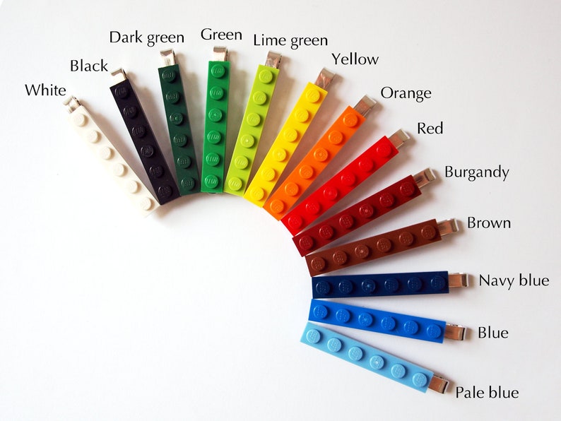 May include: A rainbow of colors in Lego bricks, arranged in a semi-circle. The colors are white, black, dark green, green, lime green, yellow, orange, red, burgundy, brown, navy blue, blue, and pale blue.