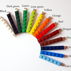 May include: A selection of USB flash drives in the shape of Lego bricks, presented in a rainbow of colours. The colours include white, black, dark green, green, lime green, yellow, orange, red, burgundy, brown, navy blue, blue, and pale blue, arranged in a semi-circle.