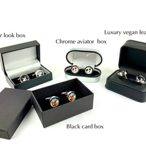 May include: An assortment of cufflinks in various cases. The cases include a leather look box, a chrome aviator box, a luxury vegan leather box, and a black card box. The cufflinks feature different designs, including a horse, a footprint, and a black and white image.