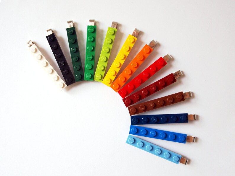 May include: A rainbow of colors in a set of 12 LEGO brick keychains. The keychains are arranged in a semi-circle, starting with white and ending with light blue.