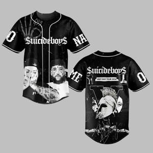 Op de afbeelding: Zwart-wit honkbalshirt met de band Suicideboys. De voorkant toont bandleden en de naam van de band. De achterkant heeft een afbeelding van een helm en de tekst "GREY DAY TOUR 2026". Witte rand en het nummer "0" zijn zichtbaar.