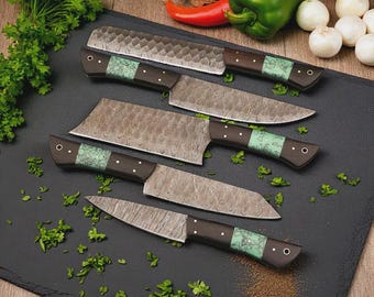 May include: Five kitchen knives with textured steel blades and dark wooden handles. Each knife has a green accent near the handle, arranged on a black cutting board. Fresh vegetables are in the background.