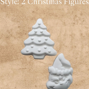 May include: A DIY Plaster Paint Kit featuring two white unpainted plaster figures: a Christmas tree with embossed circular ornaments and a Santa Claus face wearing a hat. The text reads: DIY Plaster Paint Kit Style: 2 Christmas Figures.