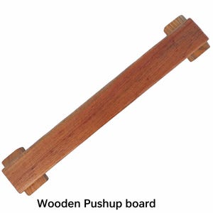 Peut inclure: Une planche de pompes en bois de forme rectangulaire. La planche est en bois brun rougeâtre et comporte deux poignées rectangulaires à chaque extrémité. Le texte "Wooden Pushup board" est au bas de l'image.