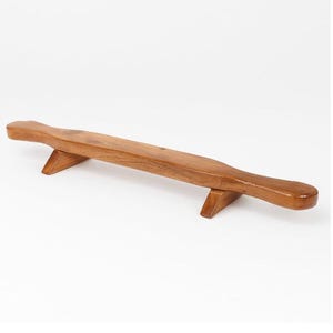 May include: A wooden rolling pin with a smooth, curved design. The rolling pin is supported by two angled wooden legs. The wood has a warm, natural tone and a polished finish, suggesting it is for kitchen use.