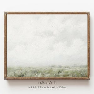 May include: A framed landscape painting with a muted color palette. The artwork depicts a field of green grass and wildflowers under a cloudy, overcast sky. The frame is a warm brown color. The text "nAotArt not All of Tone, but All of Calm" is at the bottom.