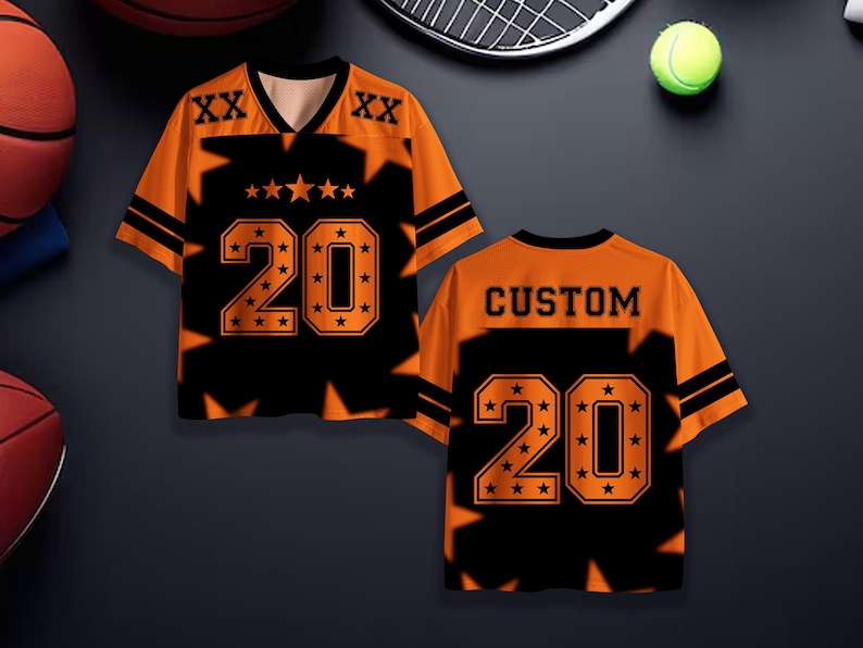 Puede incluir: Camiseta deportiva naranja y negra con el n&uacute;mero 20 y detalles de estrellas. La camiseta tiene cuello en V y mangas cortas. La parte trasera de la camiseta dice "CUSTOM" encima del n&uacute;mero 20.