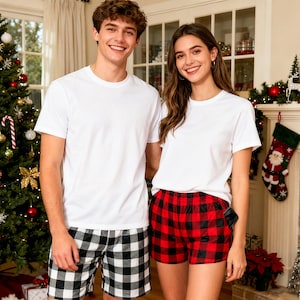 Może przedstawiać: Dwie osoby ubrane w białe koszulki i szorty w kratę. Jedna osoba ma na sobie czarno-białe szorty w kratę, a druga czerwono-czarne szorty w kratę. W tle udekorowana choinka.