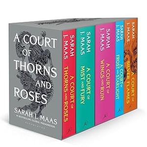 May include: A five-book box set of novels by Sarah J. Maas, featuring a gray slipcase with a black wolf illustration and the title A Court of Thorns and Roses. The spines are red, teal, pink, light blue, and orange, each with white text.