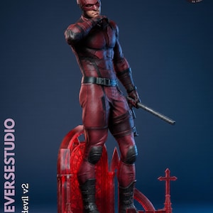 May include: A red Daredevil action figure, standing on a red base with a cross and gothic arch details. The figure is wearing a red suit, mask, and boots, holding a baton. The text "KYLEVERSESTUDIO" and "Daredevil v2" are visible.