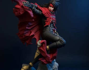 Op de afbeelding: Gedetailleerd beeldje van een personage in een dynamische pose, gekleed in een vloeiende rode cape en zwarte outfit. Het beeldje staat op een rotsachtige basis, met een wapen in de hand. Zwart haar, rode haarband. Het logo "KVSTUDIO" is zichtbaar.