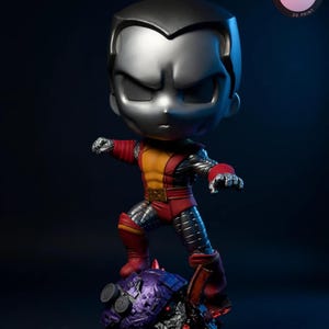 Könnte beinhalten: Stilisierte Colossus-Figur in dynamischer Pose, stehend auf einem lila-schwarzen Sockel. Die Figur hat einen silbernen Kopf, einen rot-gelben Anzug und metallische Akzente. Der Sockel trägt den Text "KyleVerseStudio".